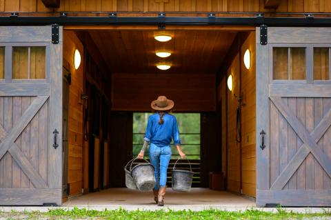 women in blue walking into a barn.